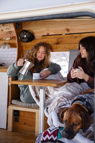 two-female-lovers-drinking-coffee-camper-van-during-winter-trip_23-2149298467